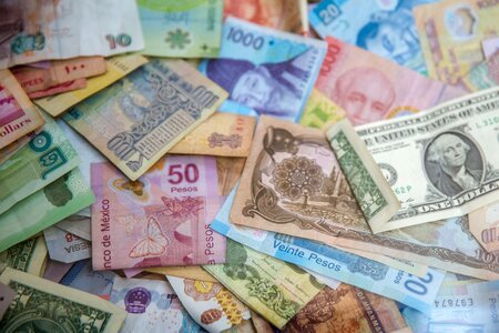 paper bank notes from various countries are stacked in a messy pile