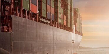 Side of a large container ship at dusk