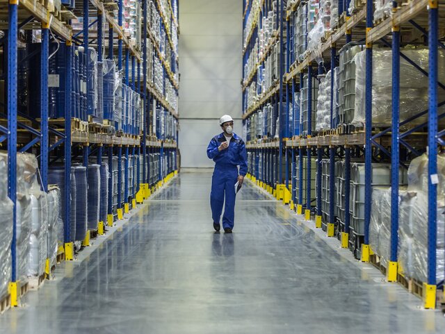 worker of warehouse with chemistry goods walking among racks