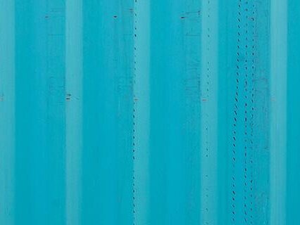 man walking past blue containers with hard hat