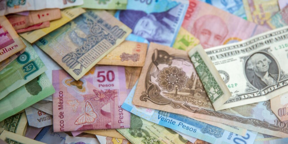 paper bank notes from various countries are stacked in a messy pile