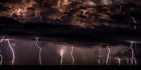 stormy clouds and several streaks of lightning hitting a dark ocean